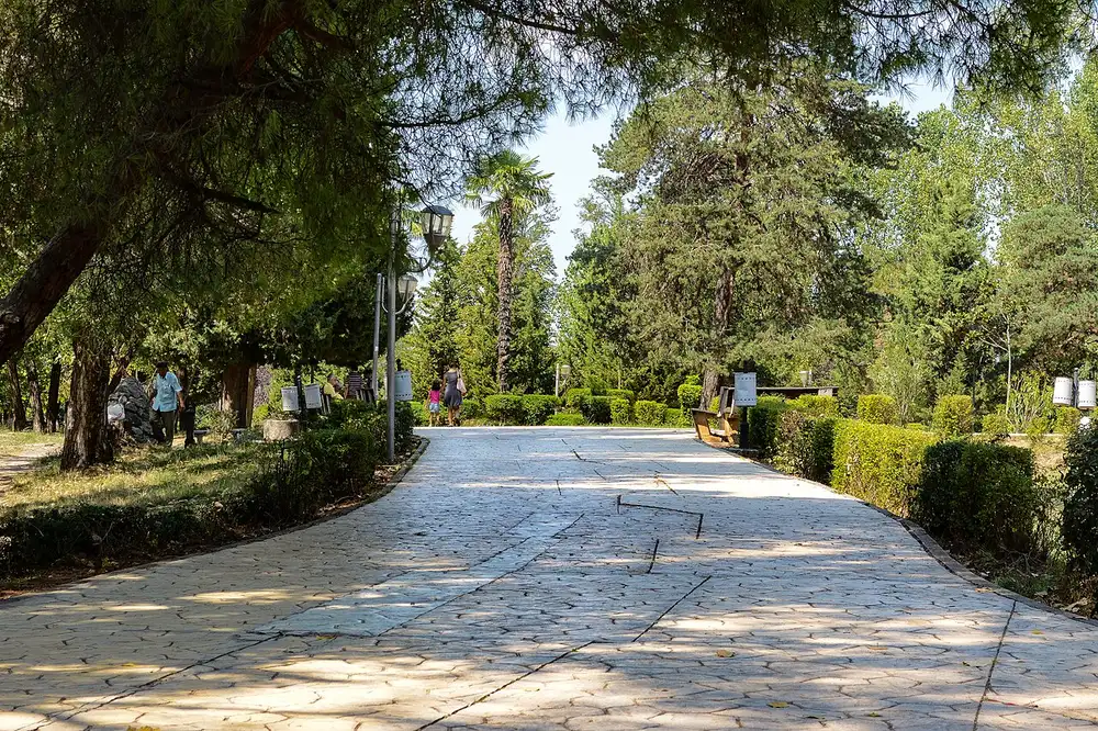 Wide green lawns, trees and paths in the Grand Park of Tirana on a clear day