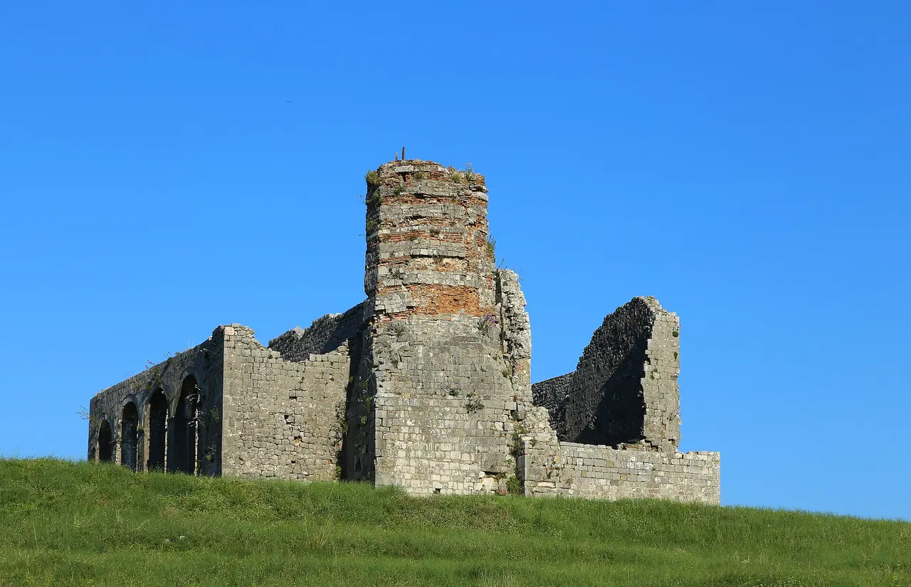 The roofless stone shell of St Stephen's church inside Rozafa Castle against a clear sky